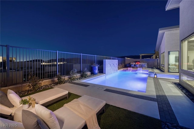 pool at night featuring a patio area, a fenced backyard, a fenced in pool, and an outdoor living space