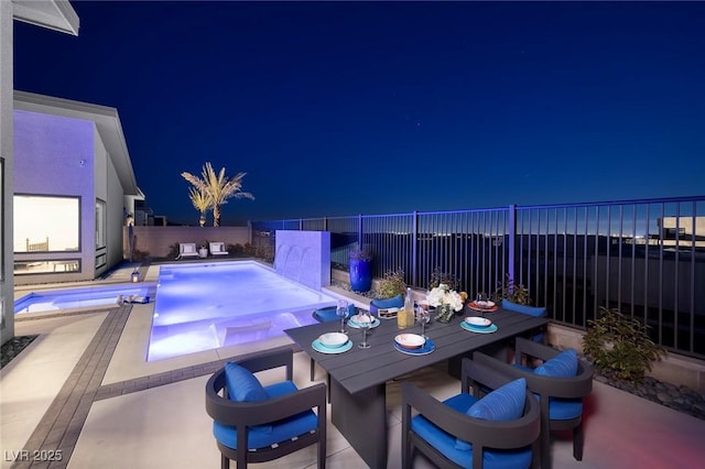 pool at night featuring a fenced backyard, an in ground hot tub, a patio, and a fenced in pool