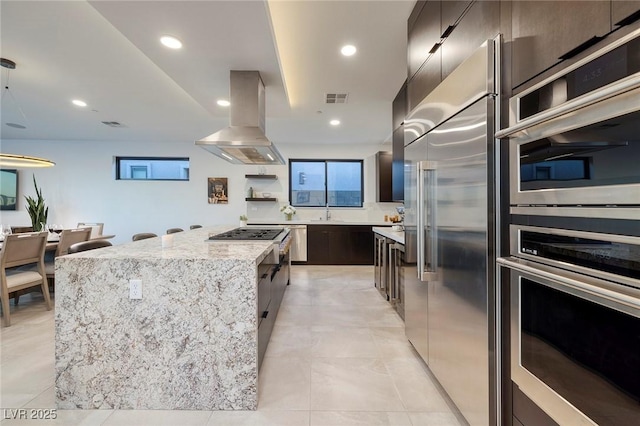 kitchen with light stone countertops, a center island, modern cabinets, ventilation hood, and appliances with stainless steel finishes