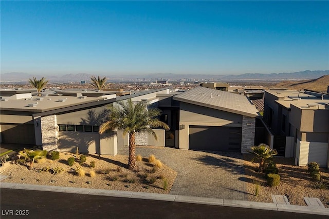 view of front of house with a garage, stucco siding, a mountain view, and driveway