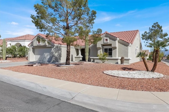 mediterranean / spanish home with a tile roof, stucco siding, a garage, and driveway