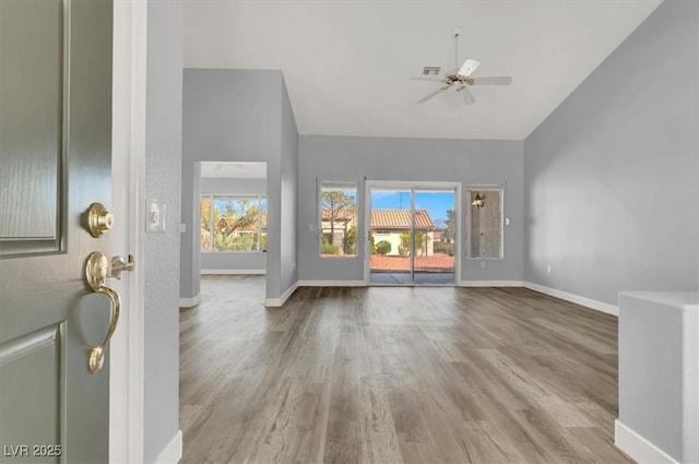 foyer entrance with high vaulted ceiling, visible vents, baseboards, ceiling fan, and wood finished floors
