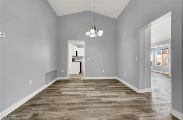 unfurnished dining area featuring baseboards, visible vents, wood finished floors, and a chandelier