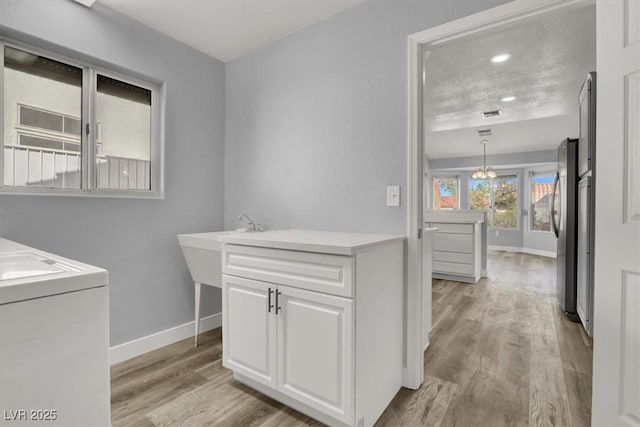 laundry room with baseboards, washer / dryer, laundry area, and light wood-type flooring