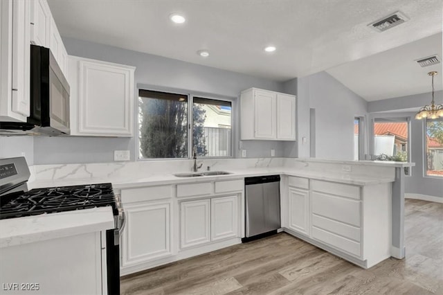kitchen featuring a sink, visible vents, appliances with stainless steel finishes, and a peninsula