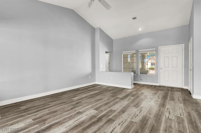 interior space with vaulted ceiling, a ceiling fan, baseboards, visible vents, and dark wood-type flooring