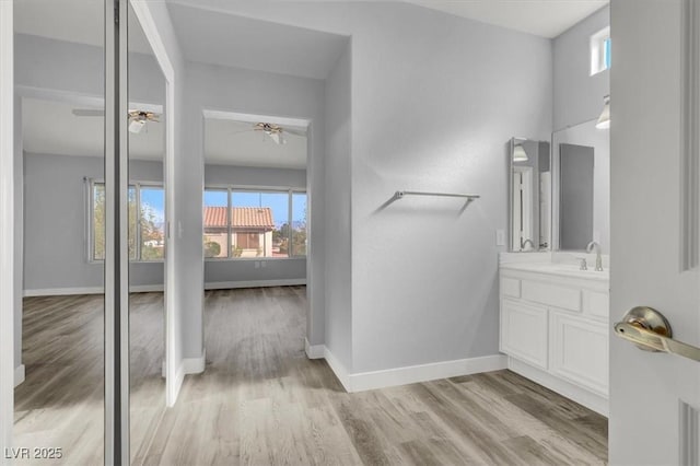 bathroom with baseboards, wood finished floors, vanity, and a ceiling fan