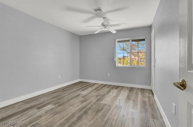spare room with baseboards, visible vents, wood finished floors, and a ceiling fan