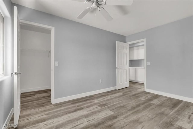 unfurnished bedroom with baseboards, wood finished floors, a closet, and a ceiling fan