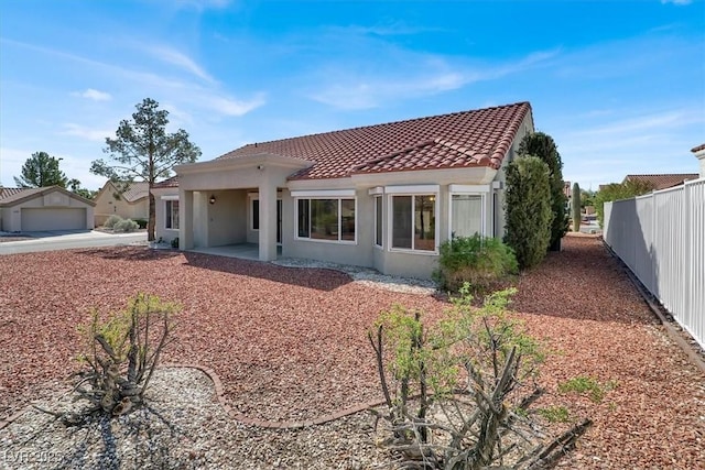 back of house featuring stucco siding, fence, a tiled roof, and a patio area