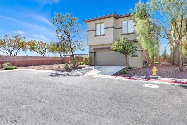 view of front of property featuring a garage, driveway, stucco siding, and fence