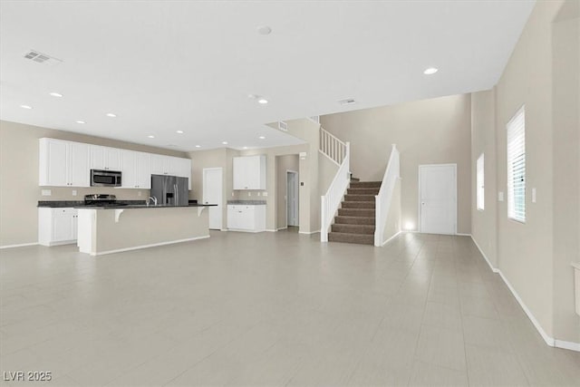 unfurnished living room with stairs, visible vents, baseboards, and recessed lighting