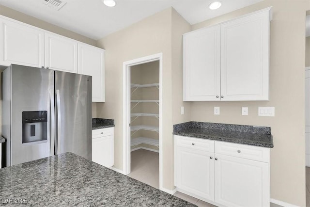 kitchen with white cabinetry, recessed lighting, stainless steel fridge with ice dispenser, dark stone counters, and visible vents
