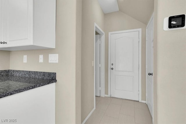 hall featuring baseboards and lofted ceiling