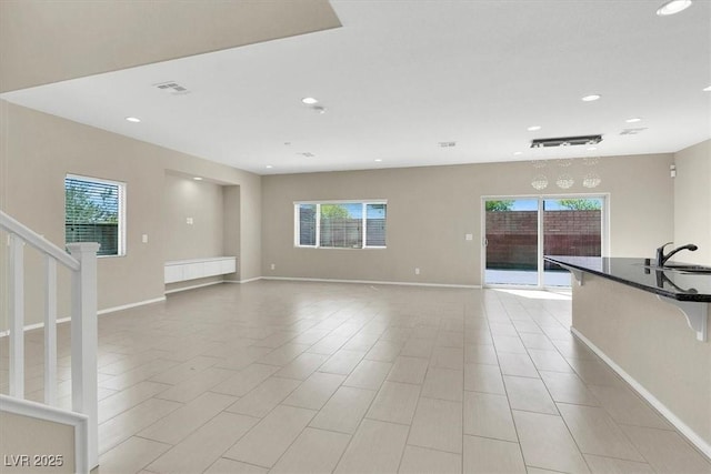 unfurnished living room with stairs, a sink, baseboards, visible vents, and recessed lighting