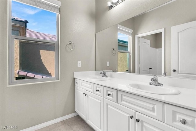 full bathroom with double vanity, a sink, tile patterned flooring, and baseboards