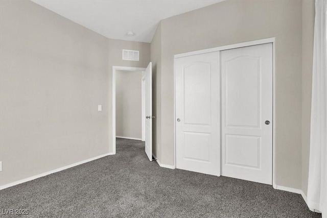 unfurnished bedroom with baseboards, visible vents, a closet, and dark carpet