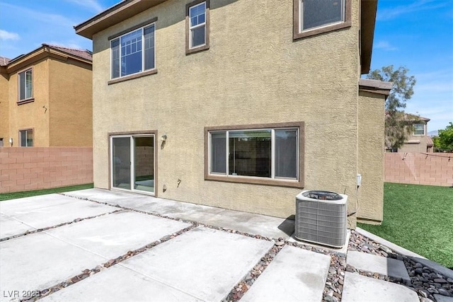 rear view of property with central AC unit, fence, stucco siding, and a patio area