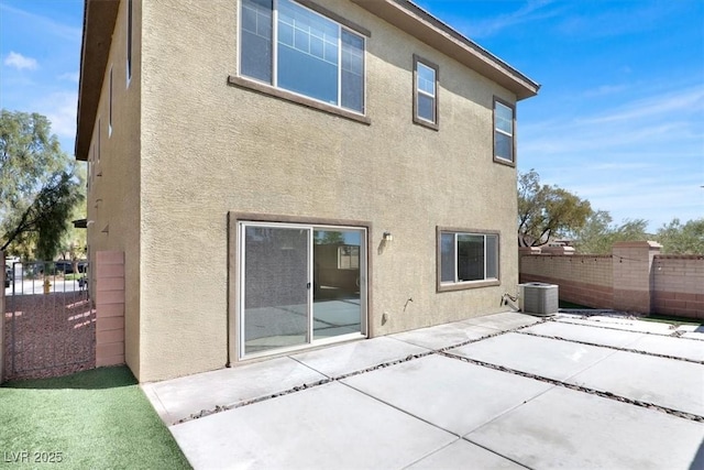 rear view of house with stucco siding, fence, and a patio