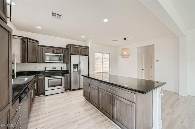 11913 Alava Ave, Las Vegas, NV 89138 - kitchen featuring stainless steel appliances, light wood finished floors, dark brown cabinetry, a kitchen island, and decorative light fixtures