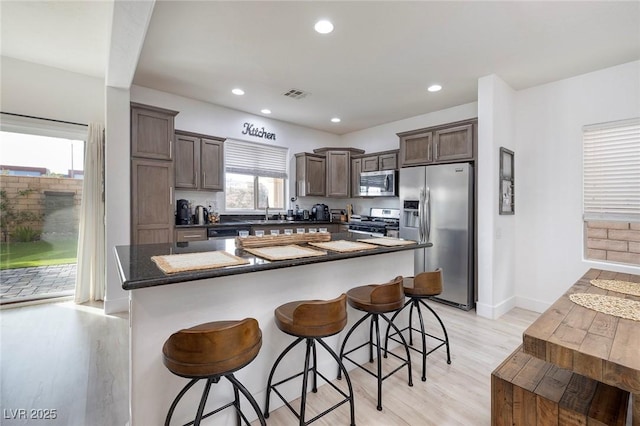 11913 Alava Ave, Las Vegas, NV 89138 - kitchen featuring stainless steel appliances, light wood finished floors, dark brown cabinets, recessed lighting, and a center island