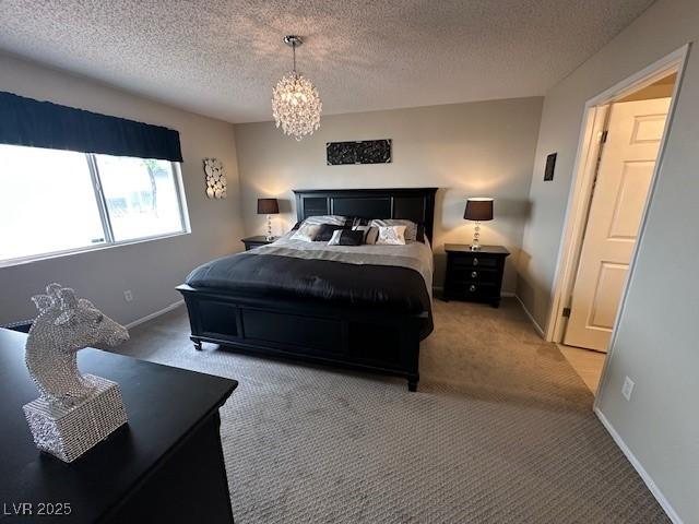 7900 Fossil Creek Ln Unit 103, Las Vegas, NV 89145 - bedroom featuring baseboards, carpet flooring, a textured ceiling, and an inviting chandelier