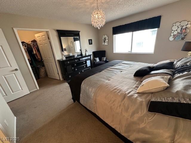 7900 Fossil Creek Ln Unit 103, Las Vegas, NV 89145 - carpeted bedroom with a textured ceiling, a closet, a notable chandelier, and a walk in closet