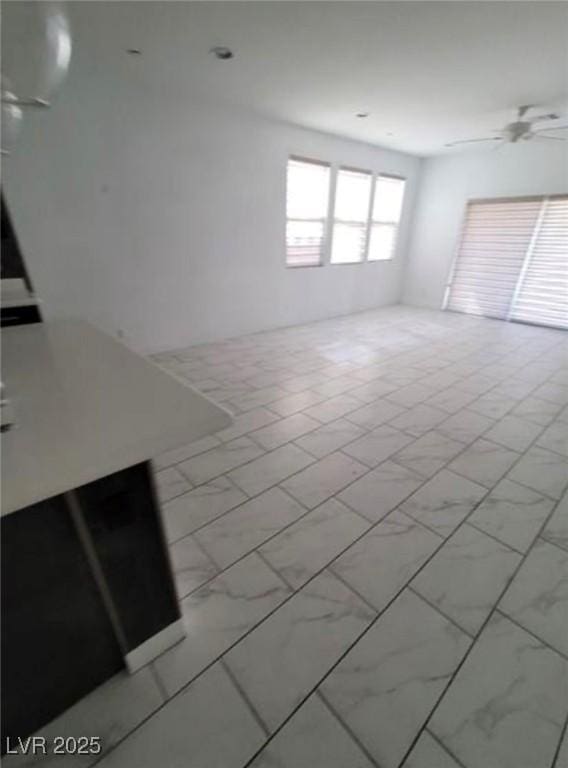 unfurnished living room featuring marble finish floor and a ceiling fan