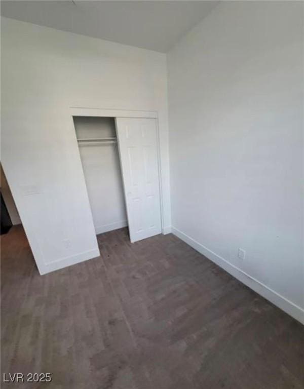unfurnished bedroom featuring a closet, wood finished floors, and baseboards