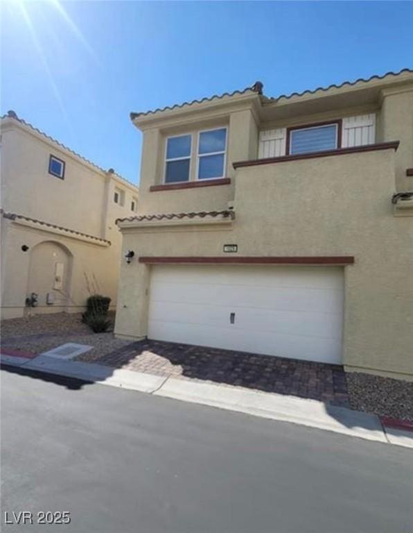 view of front of home featuring an attached garage, driveway, stucco siding, and a tile roof