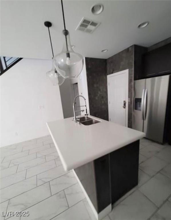 kitchen with stainless steel fridge with ice dispenser, light countertops, visible vents, marble finish floor, and a sink