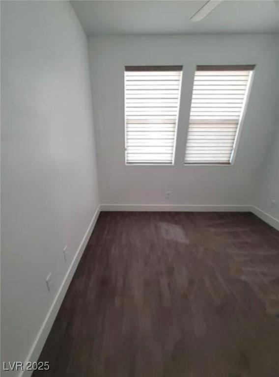 unfurnished room featuring dark wood-style flooring, baseboards, and plenty of natural light