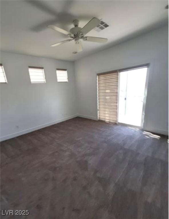 empty room featuring dark wood-style floors, visible vents, baseboards, and ceiling fan