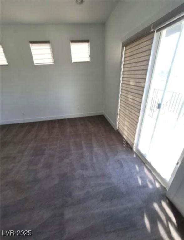 empty room featuring baseboards and dark carpet