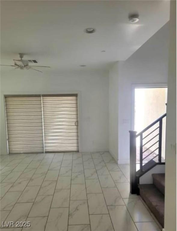 spare room featuring marble finish floor and a ceiling fan
