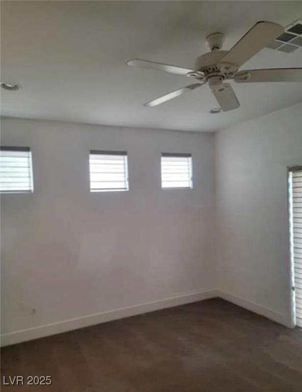 empty room with baseboards, a ceiling fan, and visible vents