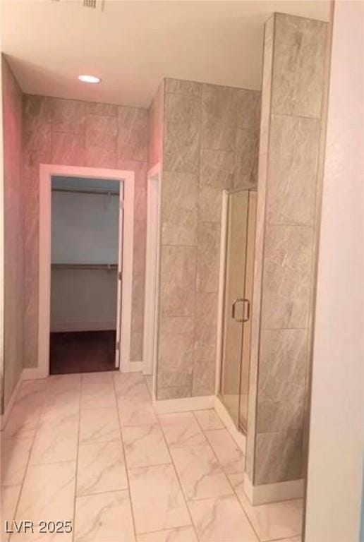 full bathroom with a shower stall, marble finish floor, and tile walls