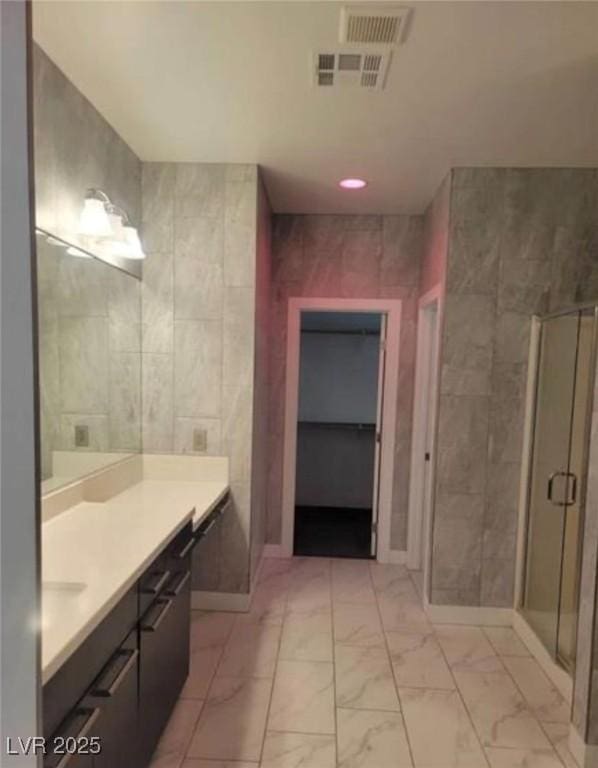 bathroom featuring visible vents, tile walls, a shower stall, vanity, and marble finish floor