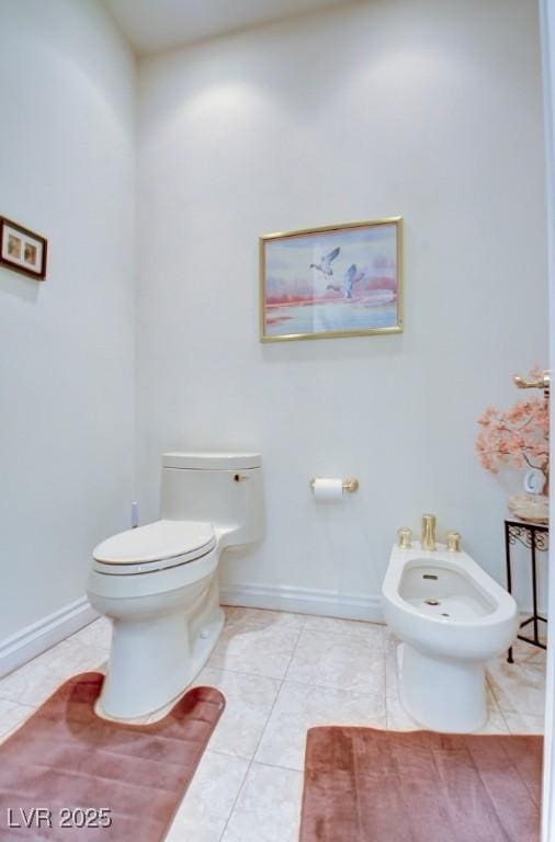 bathroom with baseboards, a bidet, tile patterned floors, and toilet