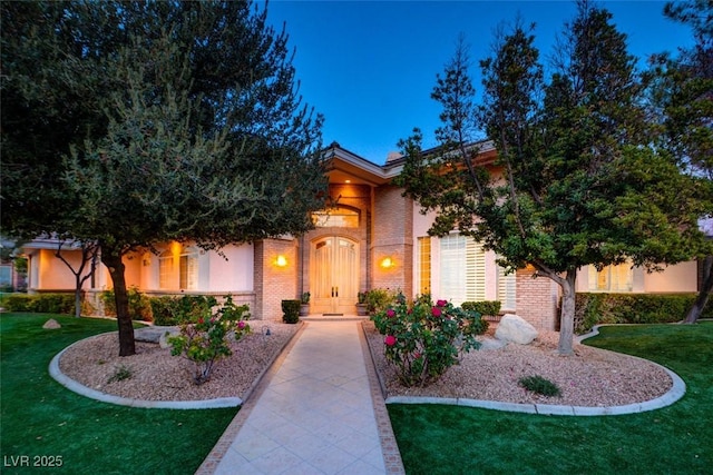 mediterranean / spanish-style home with brick siding and a front lawn