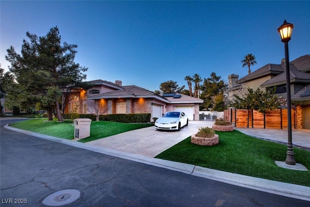 single story home featuring a garage, fence, a front yard, driveway, and solar panels