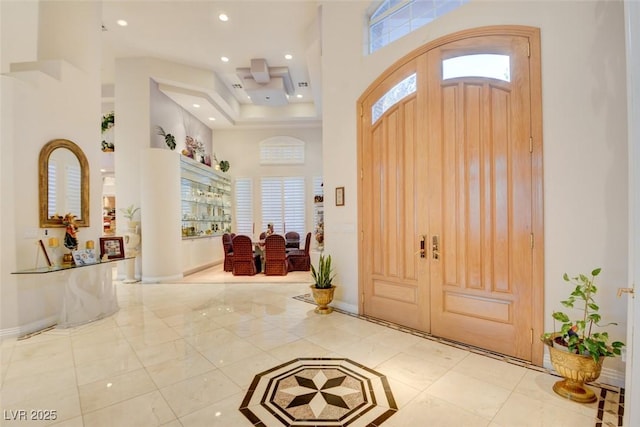 foyer entrance featuring recessed lighting, baseboards, a healthy amount of sunlight, and a towering ceiling