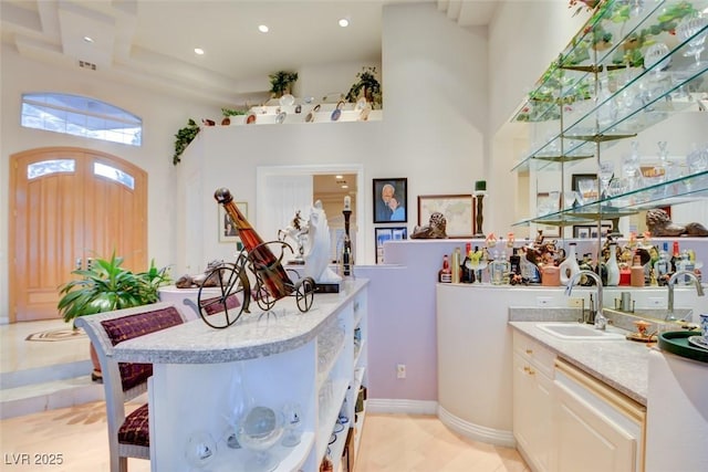 bar featuring indoor wet bar, recessed lighting, a sink, and a towering ceiling