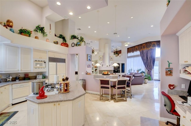 kitchen featuring built in appliances, a kitchen island, open floor plan, light countertops, and light tile patterned floors