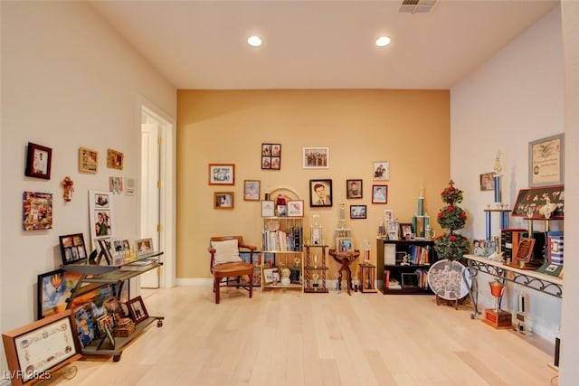living area featuring a towering ceiling, recessed lighting, wood finished floors, and visible vents