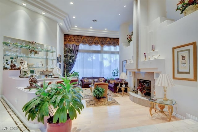 living area featuring recessed lighting, baseboards, a high ceiling, and a premium fireplace