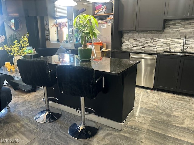 kitchen with dark stone counters, a kitchen bar, tasteful backsplash, dishwasher, and a sink
