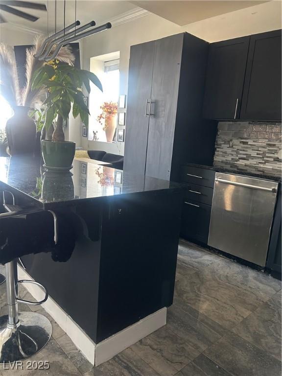 kitchen featuring tasteful backsplash, dark countertops, crown molding, dark cabinets, and dishwasher