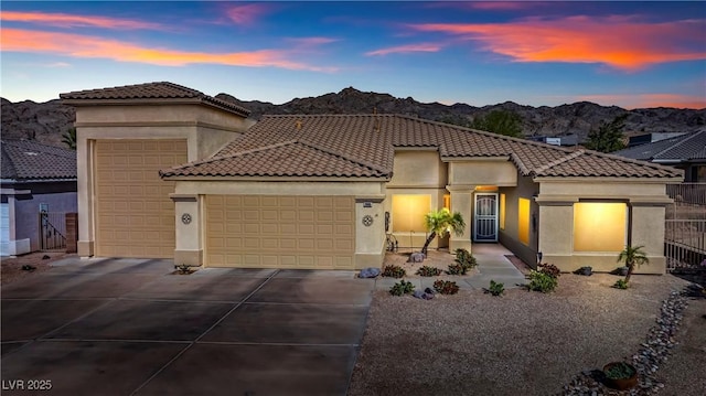 mediterranean / spanish-style home with stucco siding, an attached garage, concrete driveway, and a mountain view