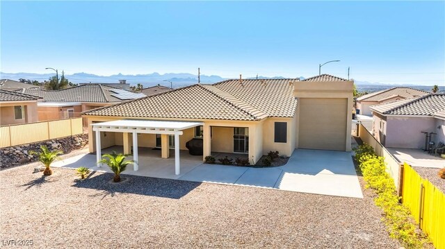 back of house featuring a tile roof, a fenced backyard, a mountain view, driveway, and stucco siding